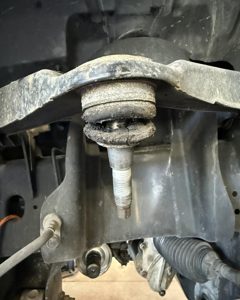 Worn ball joint with a torn, dirt-packed boot